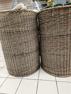 Two tall handwoven willow display baskets standing side by side on a white tiled shop floor