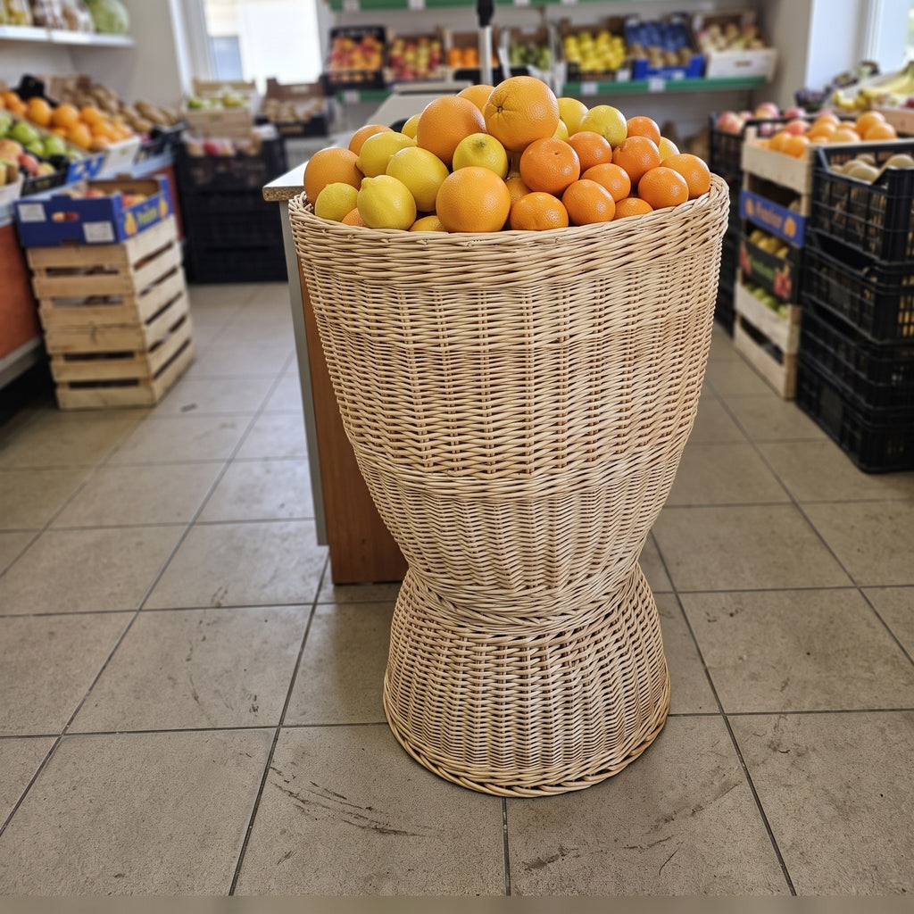 Tall willow produce display basket full of oranges and lemons on the tiled floor of a greengrocer's shop
