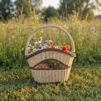 Tall wicker basket with handle filled with cornflowers and poppies, standing in a summer wildflower meadow at sunset