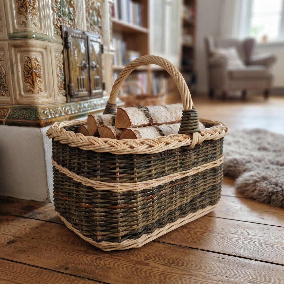 Rectangular wicker basket with handle used as a firewood holder with birch logs beside a tiled stove in a cosy living room