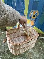 Hand carrying an empty willow basket by its wrapped handle in front of a colourful street art mural