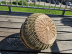 Close-up of the radial woven base of the round handwoven willow basket, turned upside down on a sunny wooden balcony table