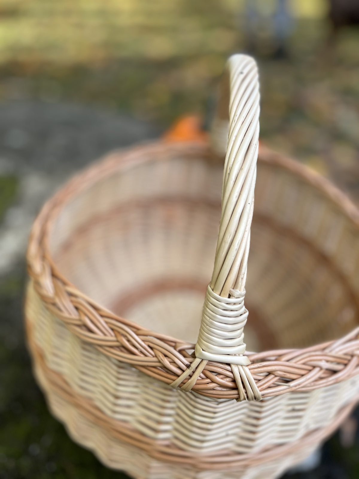 Close-up of the round basket's twisted handle and braided rim, showing the tight hand weave