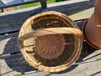Round handwoven willow basket seen from above at an angle, showing its deep open interior, circular woven base and braided rim