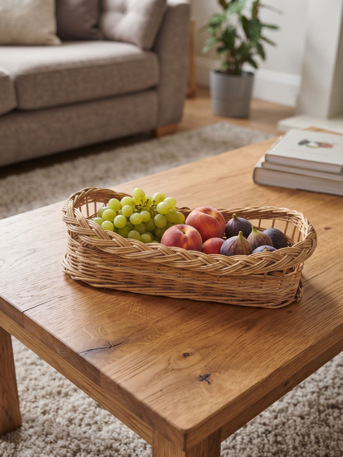 Willow serving tray with braided rim holding grapes, peaches and figs on a wooden coffee table in a living room