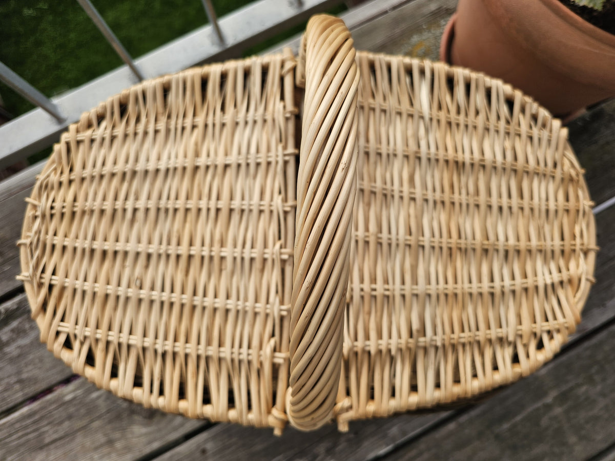 Top view of the oval willow picnic hamper showing the two woven lids closed and the centre handle between them.