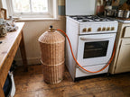 Willow gas bottle cover in a rustic kitchen next to a gas cooker, with the regulator and orange hose coming out of the opening at the top