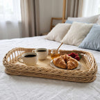 Wicker breakfast in bed tray with two cups of coffee, honey, croissants and strawberries on a bed with linen pillows