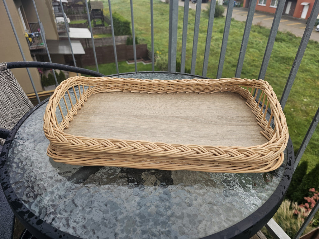 Large wicker ottoman tray with wooden base and braided rim, shown whole on a round glass balcony table