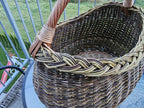 Inside view of the deep oval willow basket on a balcony table, showing the open weave, braided rim and the handle bound into the side.