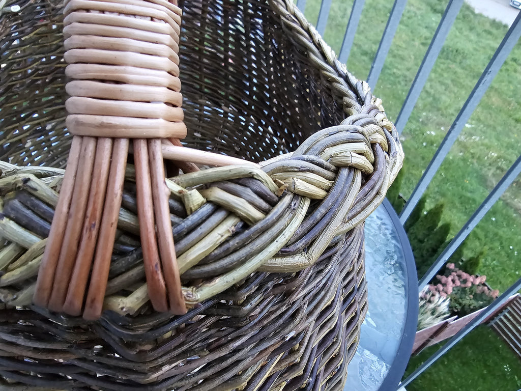 Close-up of where the multi-rod willow handle is bound into the thick hand-braided rim of the deep oval foraging basket.