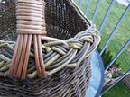 Close-up of where the multi-rod willow handle is bound into the thick hand-braided rim of the deep oval foraging basket.