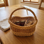 Small wicker gift basket with handle and ribbon bow filled with jars, a lavender sprig and soap on a wooden table