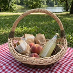 Round wicker trug with handle packed with sandwiches, peaches and lemonade on a red checked picnic blanket by a lake