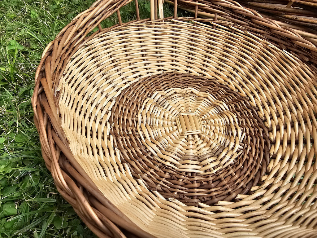 Close-up of the willow trug's round woven base spiralling out from the centre inside the rope-like braided rim