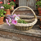 Wicker garden trug with handle holding cosmos, lavender and wildflowers on old wooden steps among potted geraniums