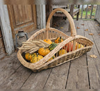 Willow harvest trug with handle holding small pumpkins, gourds and wheat ears on a wooden porch in autumn