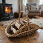 Large open-weave willow basket with handle used as a log basket for firewood and pine cones by a wood stove