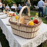 Weinkorb aus Weide für 6 Flaschen mit Trennwänden und Henkel, darin Saft und Limonade, auf einem Tisch bei einer Gartenparty