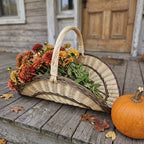 Large willow flower gathering trug with tall handle filled with zinnias and dahlias on a wooden porch beside a pumpkin