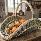 Handwoven willow garden trug filled with apples, small pumpkins and walnuts on a farmhouse kitchen table with copper pans behind.