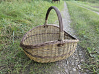 Three-quarter view of the wicker basket in the grass beside a country track.