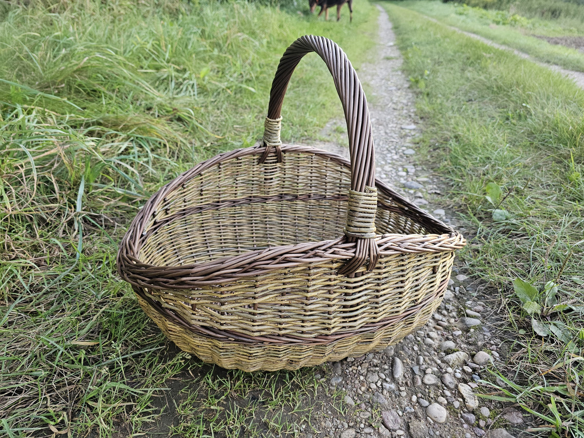 Three-quarter view of the wicker basket in the grass beside a country track.