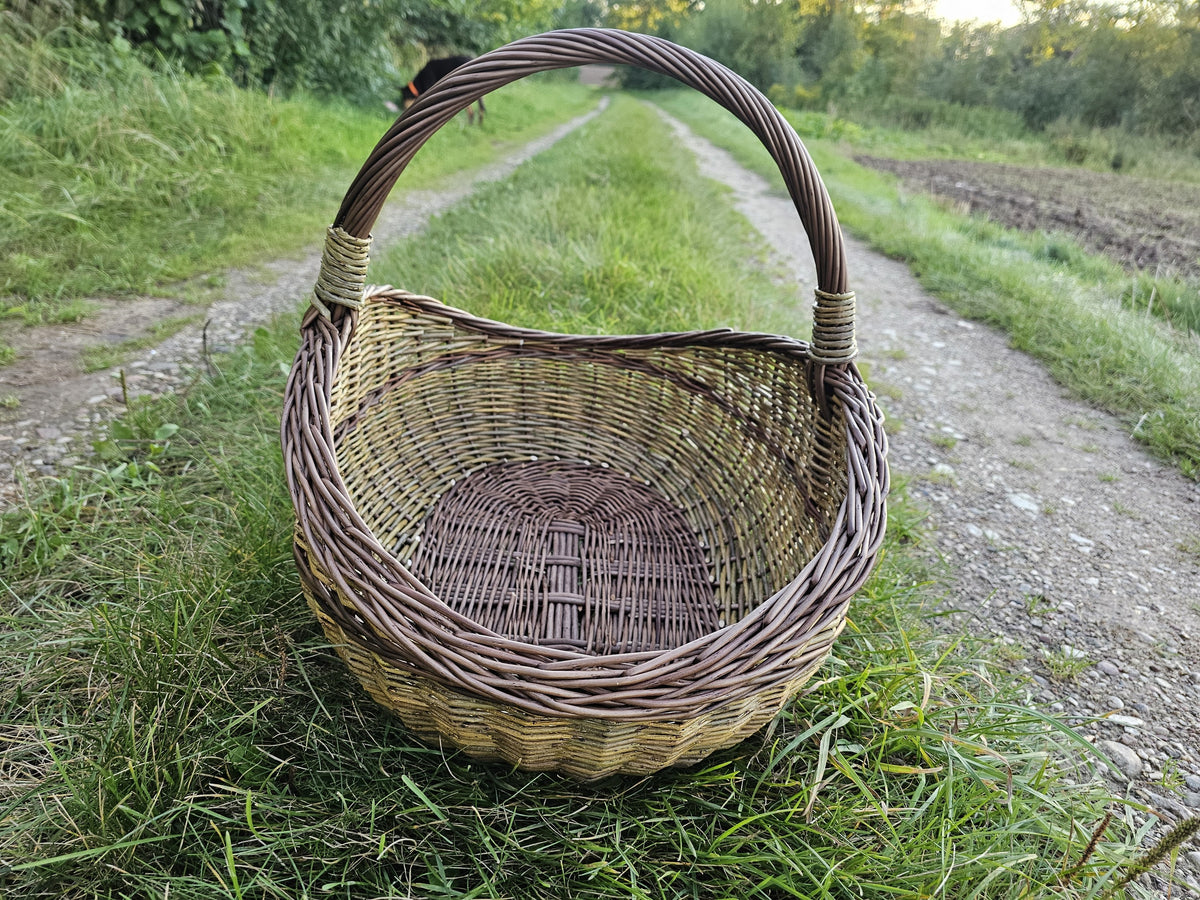 Wicker gathering basket standing on the grass verge with the track running away behind it.