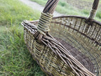 Close view of the plaited rim of the willow gathering basket and the wrapped joint where the twisted handle meets the side