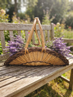 Willow flower trug with a tall arched handle filled with fresh lavender bunches on a weathered wooden garden bench in summer.