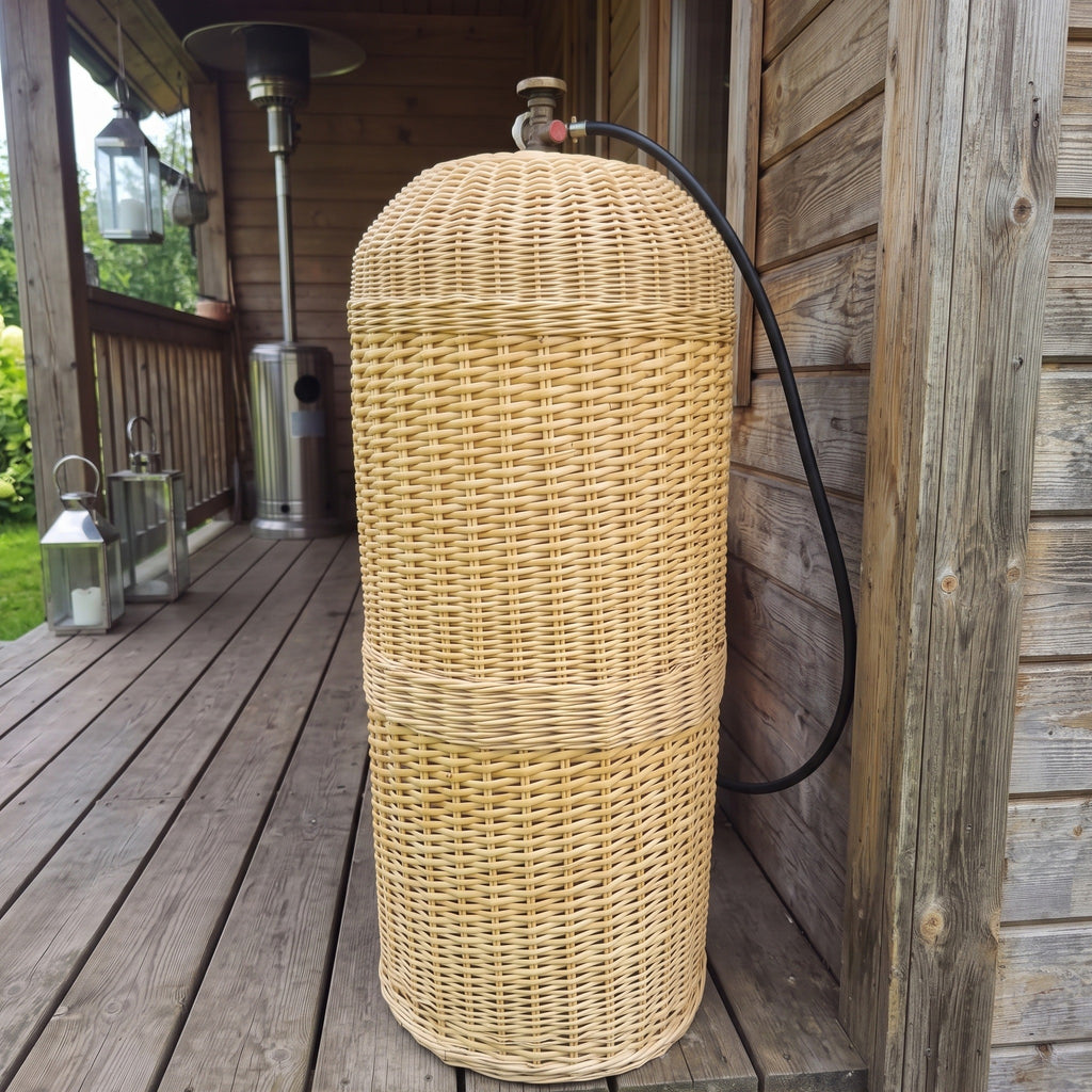 Gas bottle cover for a 50L cylinder, handmade from woven willow, hiding the LPG tank on a wooden terrace with only the valve and hose showing.