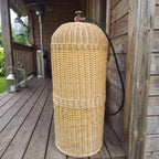 Gas bottle cover for a 50L cylinder, handmade from woven willow, hiding the LPG tank on a wooden terrace with only the valve and hose showing.