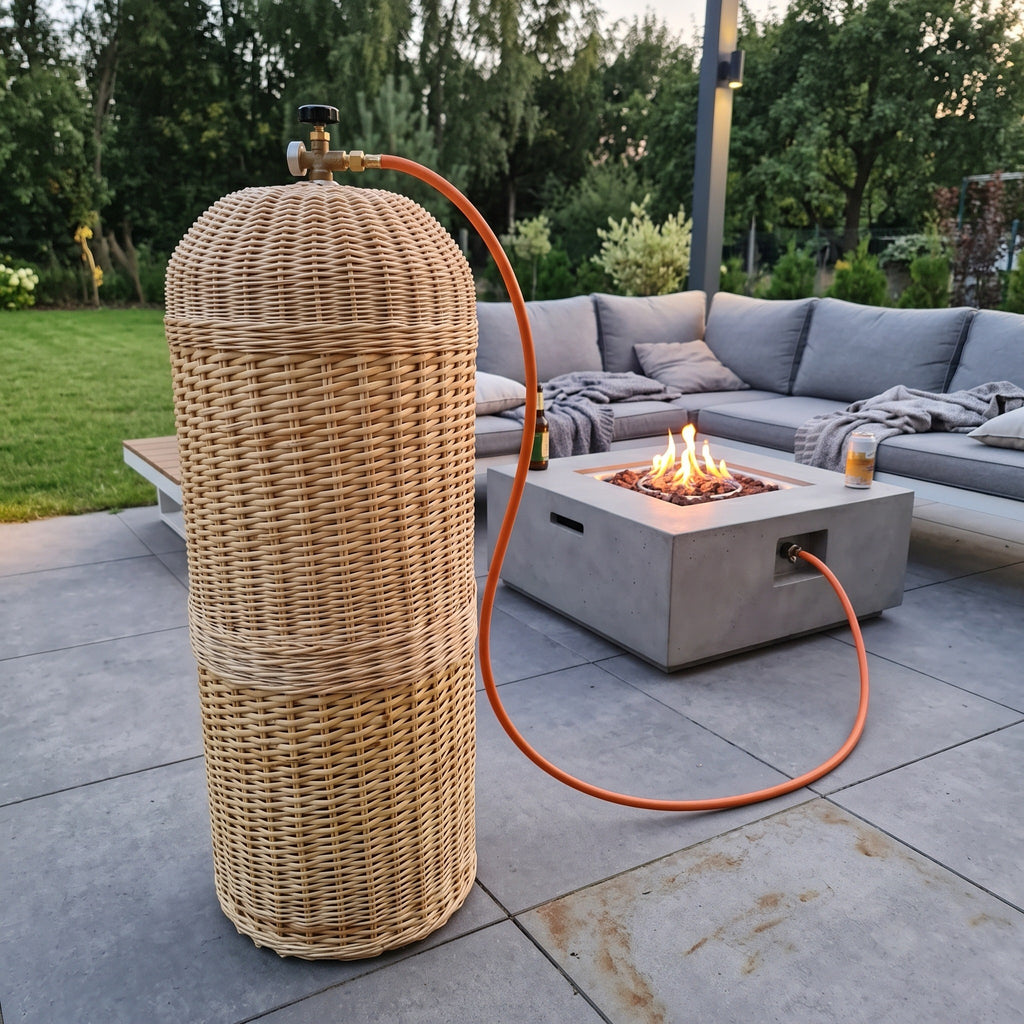 Wicker gas bottle cover beside a concrete fire pit table on a modern terrace with an outdoor sofa, the hose running to the burner.