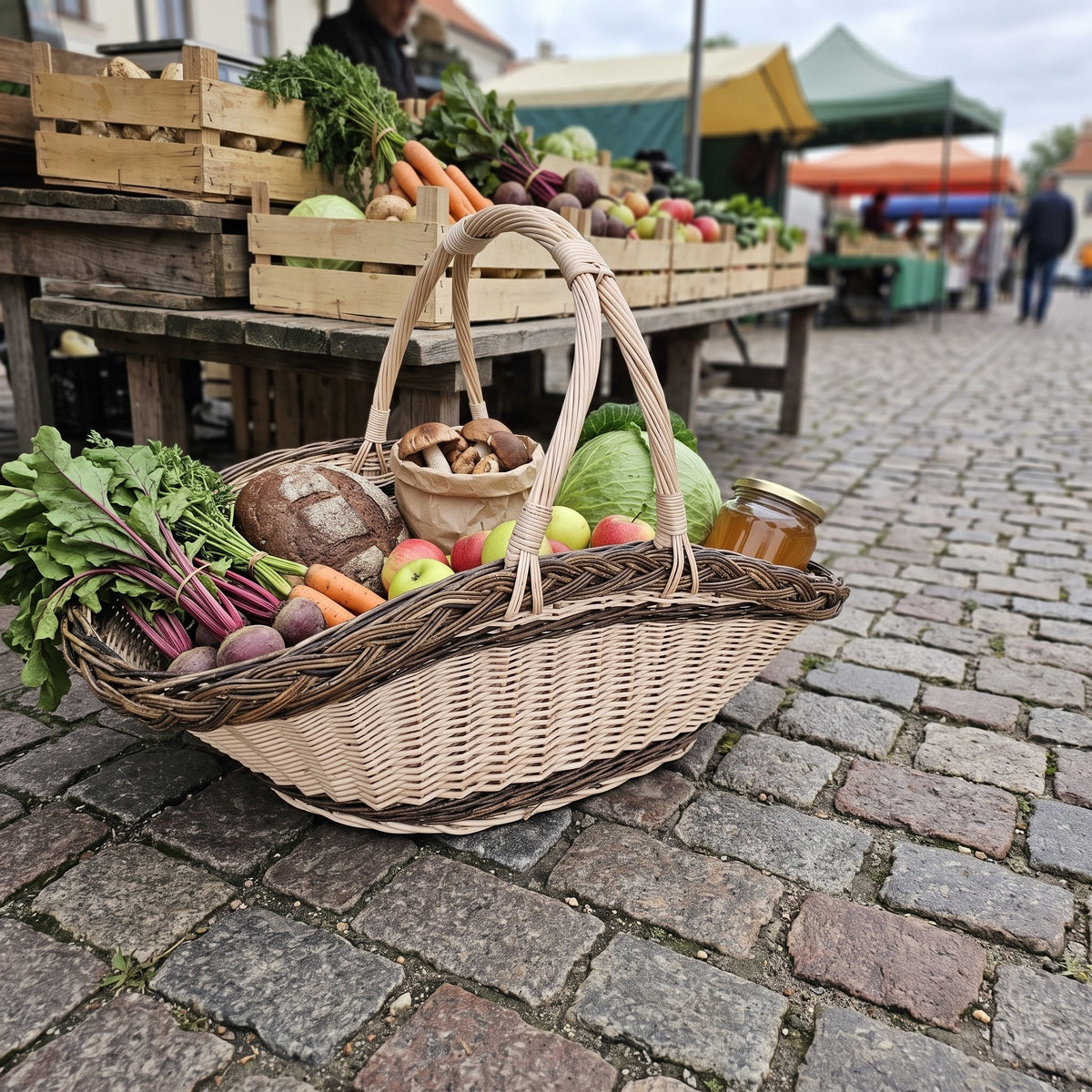 Handwoven harvest basket with two handles packed with beetroot, carrots, apples, cabbage, bread and mushrooms at a cobblestone street market