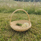 Small handwoven willow basket with a tall handle on a summer meadow, holding a bunch of daisies and fresh herbs