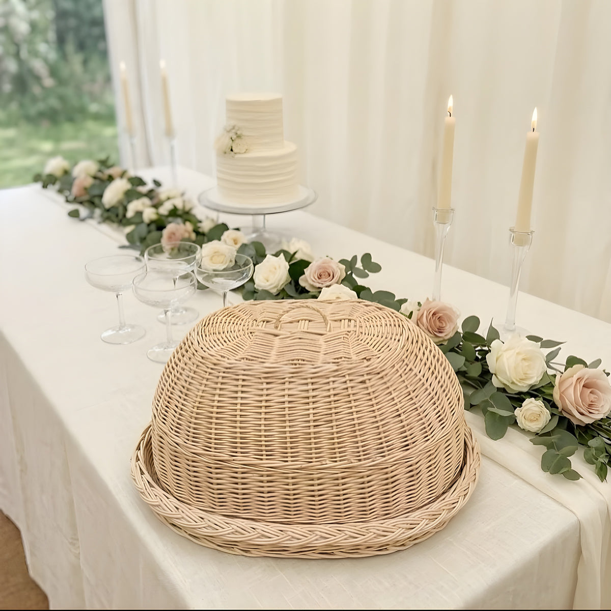 Oval willow food cover dome with matching tray on a wedding reception table with roses, candles and a white tiered cake