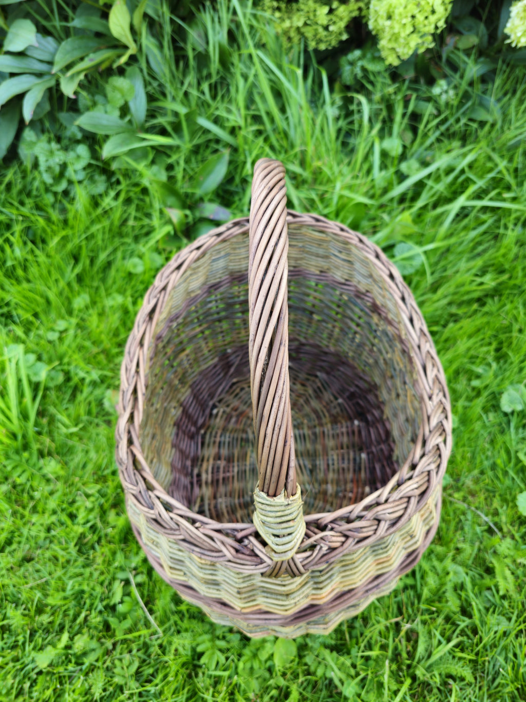 Overhead view with the arched handle running across the mouth, showing how it is twisted from several rods and bound at the join.
