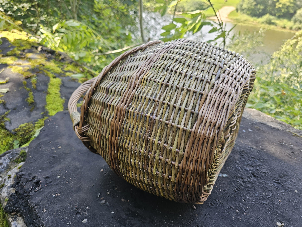 The basket tipped onto its side on rock, showing the closed weave of the wall and the shaping of the base.