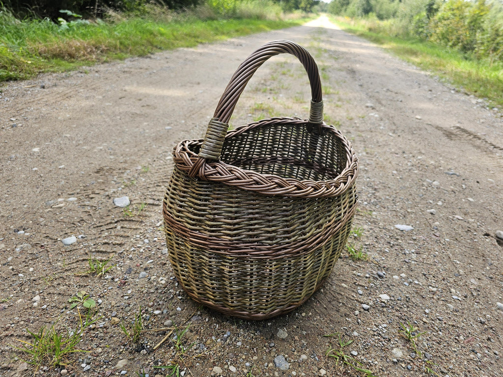 Wicker basket on a gravel country track, the road running away behind it and the weave lit from the side.