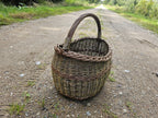 Wicker basket on a gravel country track, the road running away behind it and the weave lit from the side.