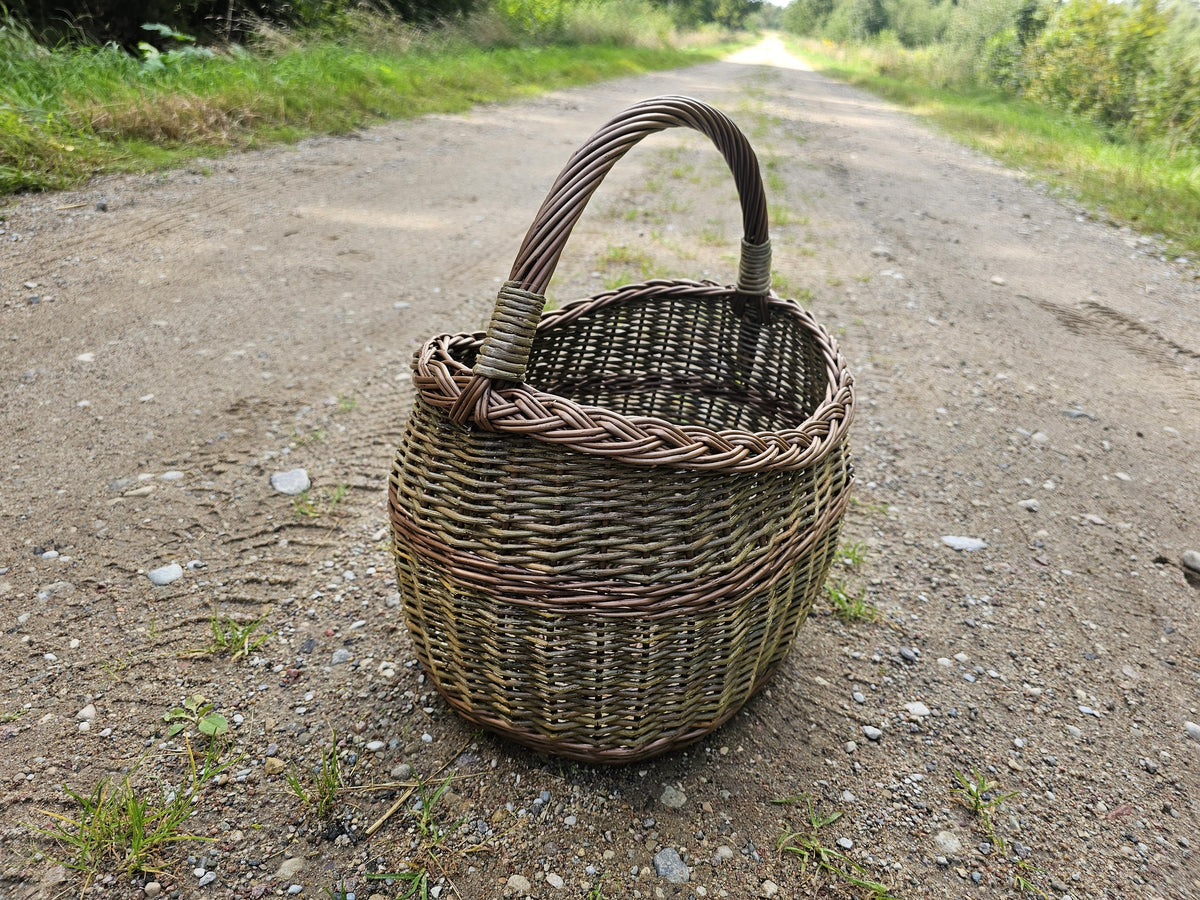 Wicker basket on a gravel country track, the road running away behind it and the weave lit from the side.