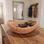 Small willow bowl with braided rim used as a catch-all for a wallet and sunglasses on a wooden hallway dresser