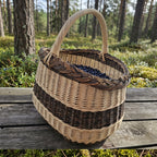 Oval wicker foraging basket with handle filled with wild blueberries on a wooden bench in a pine forest