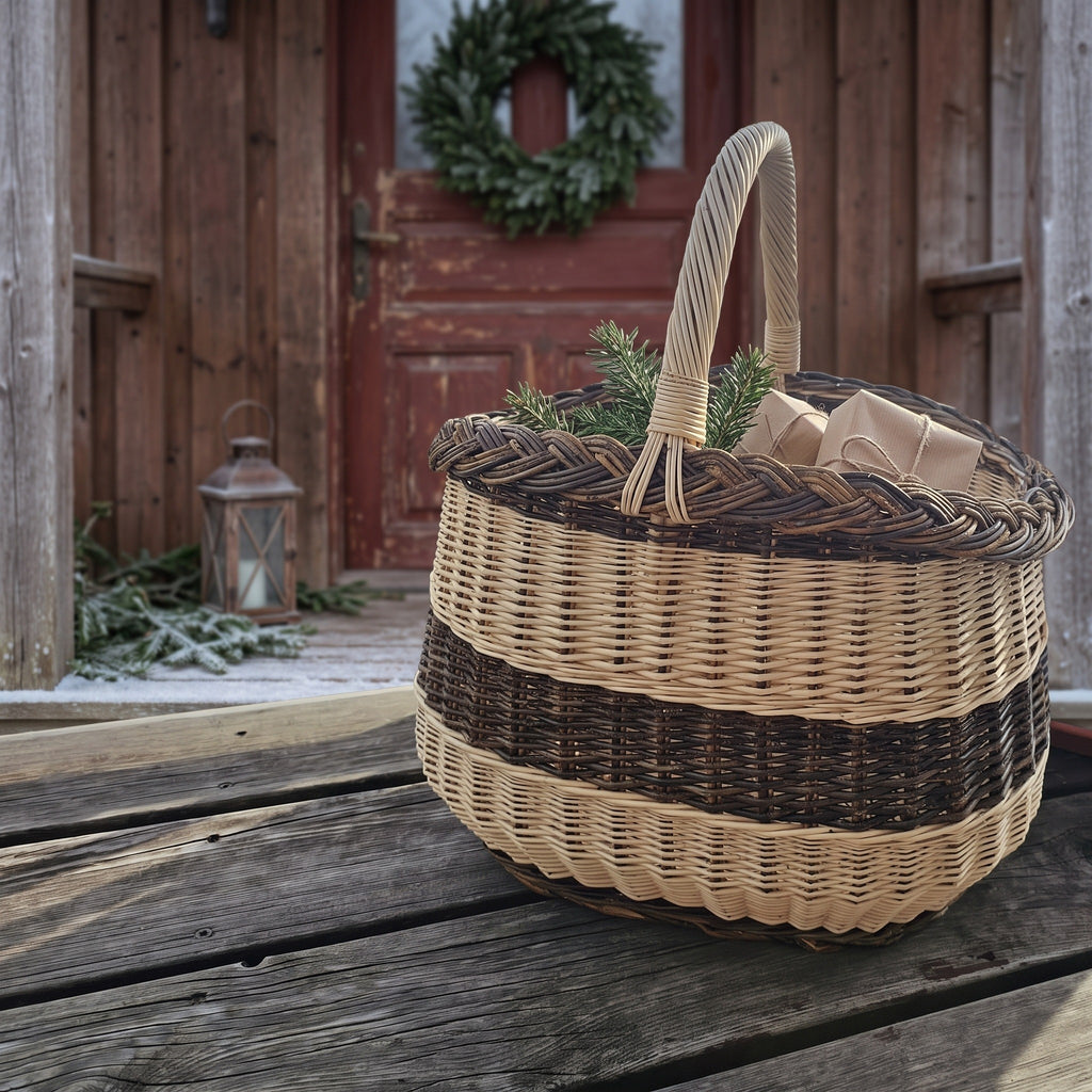 Willow market basket with twisted handle holding small wrapped gifts and fir sprigs on a wooden porch by a door with a Christmas wreath