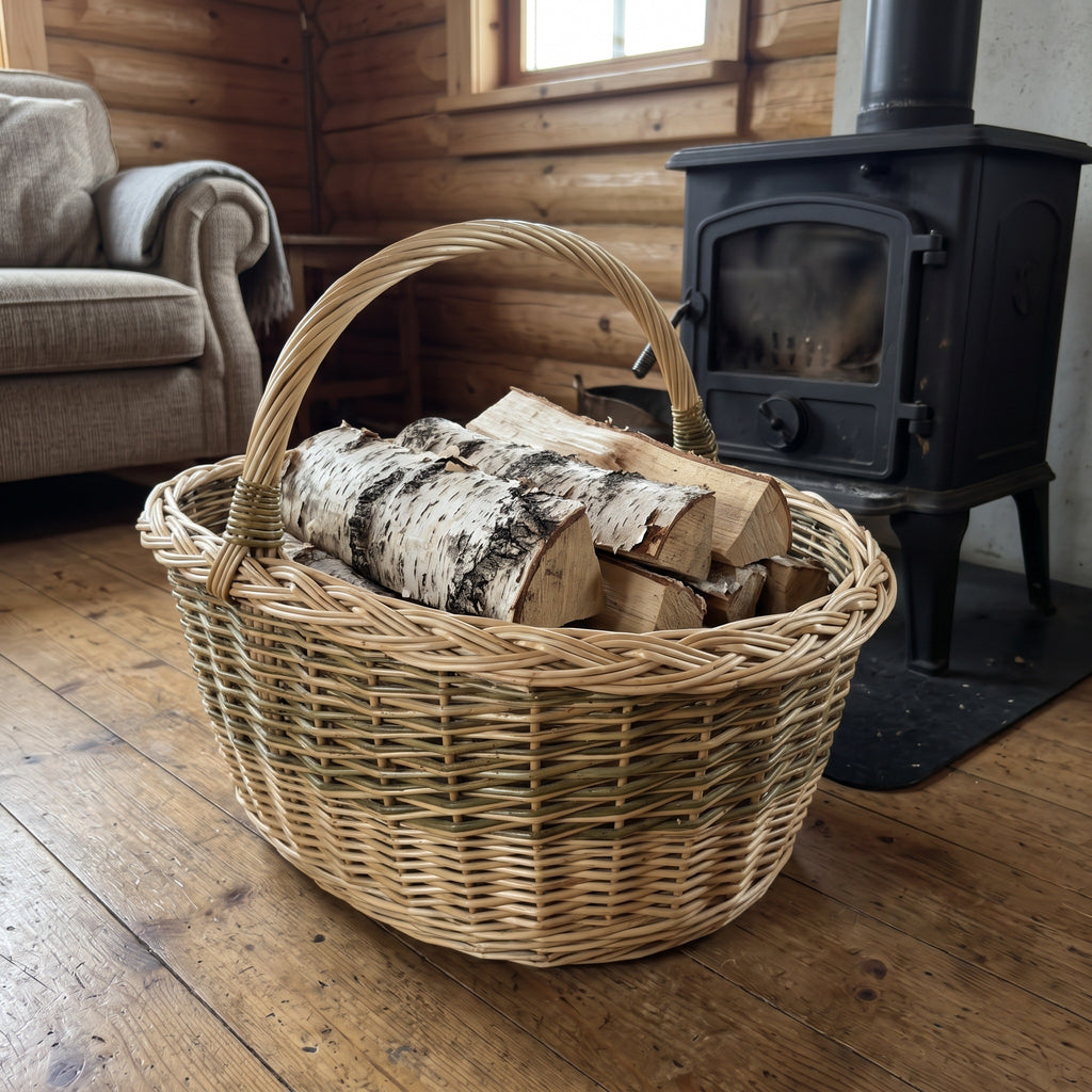 Large wicker firewood basket with tall handle holding birch logs beside a wood stove in a cosy log cabin living room