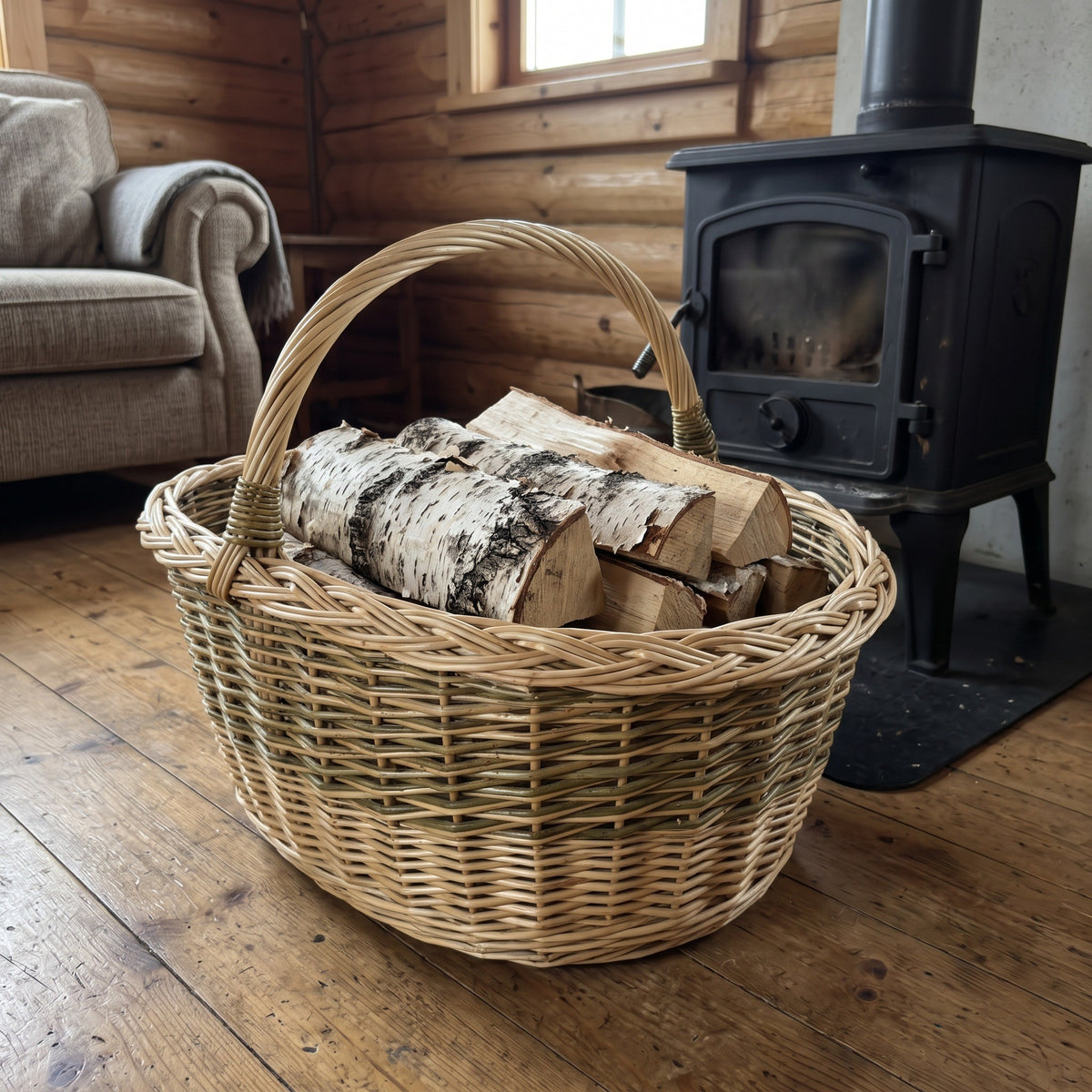 Large wicker firewood basket with tall handle holding birch logs beside a wood stove in a cosy log cabin living room