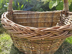 Close-up of the thick braided border and woven divider panel of the handwoven willow picnic basket in a garden.