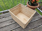 Large willow storage basket from above, showing the open top and the wooden board base