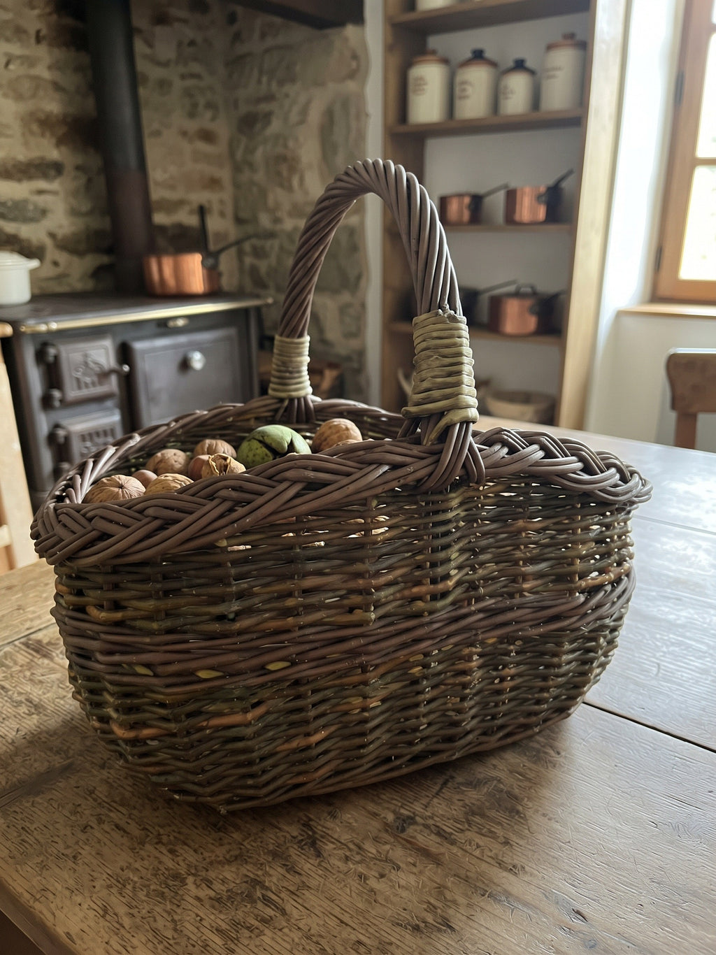 Small willow basket with a braided rim holding walnuts on a rustic kitchen table beside an old cast iron stove