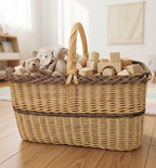 Large rectangular willow toy storage basket with handle filled with teddy bears and wooden building blocks in a bright playroom.